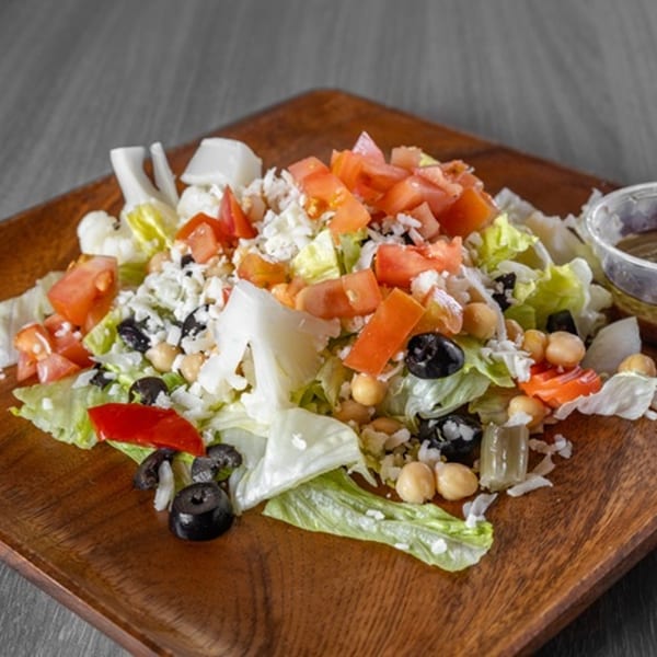 A fresh Ameci Pizza Kitchen salad with lettuce, tomatoes, olives, chickpeas, and feta cheese.